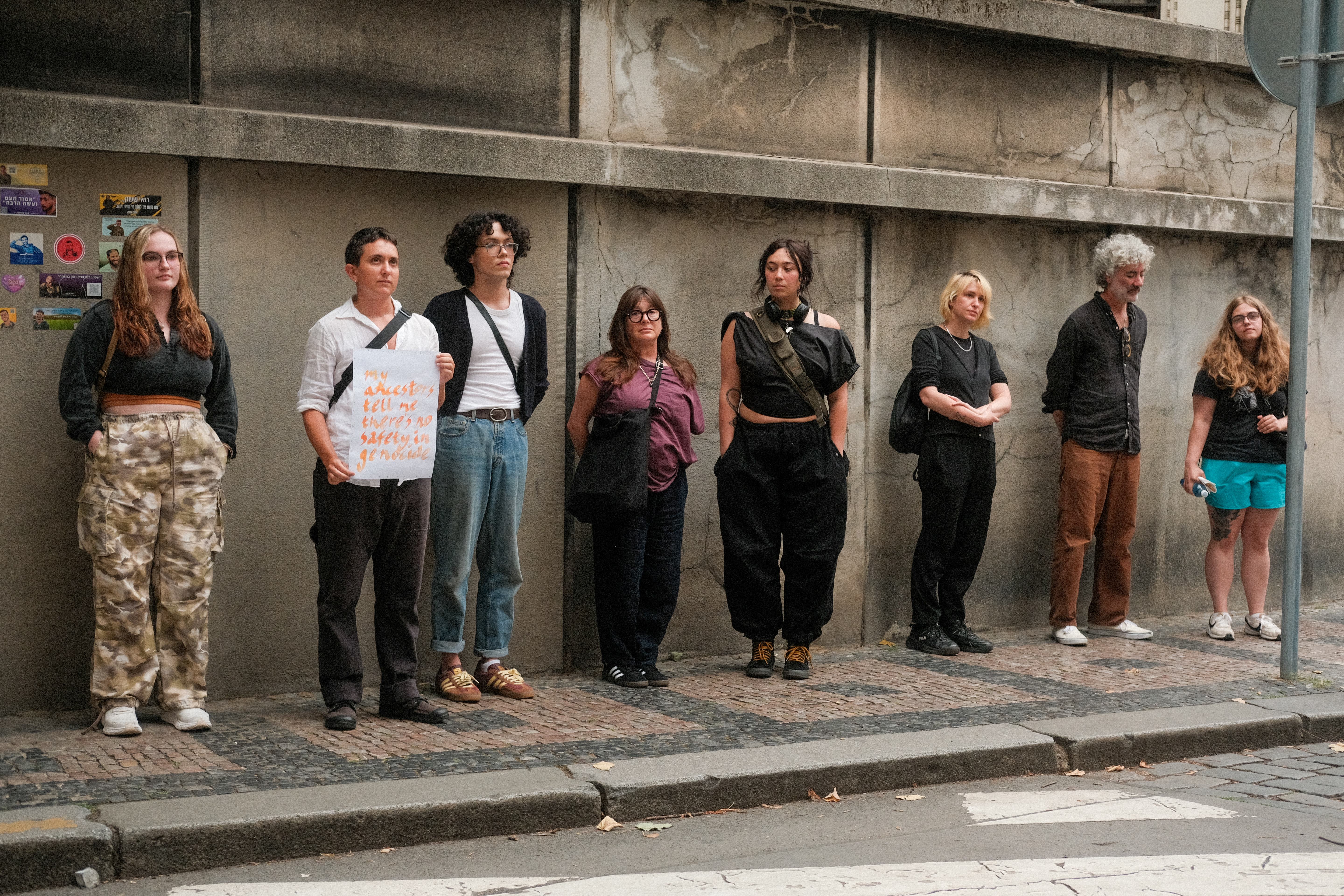 a group of people stand in front of a cemetery wall