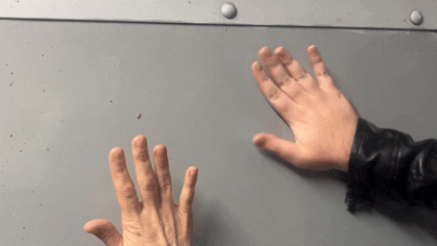 two white hands knocking and drumming on a metal surface